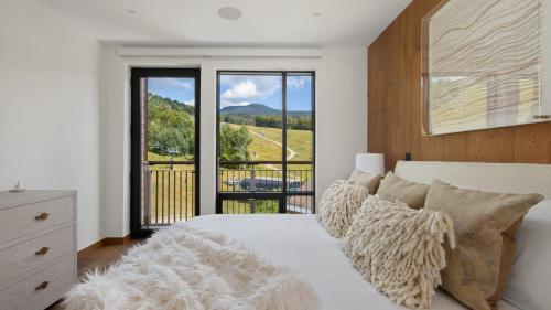 a bedroom with a white bed and a balcony at 4F One Spruce Peak Stowe Mountain Resort Ski in Ski Out 4 bed Sleeps 10 in Stowe