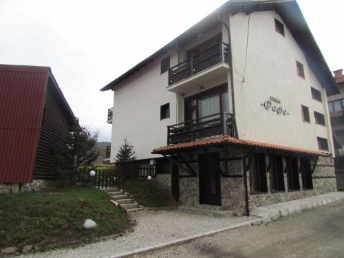 a white building with a balcony on the side of it at Guest House Raffe in Dobrinishte