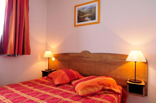 una camera da letto con un letto con due lampade sopra di Résidence Goélia Les Chalets de la Toussuire a La Toussuire