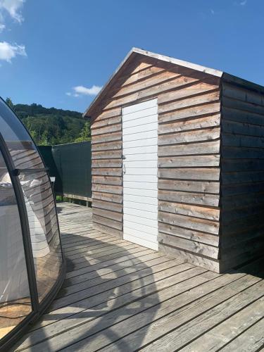 a wooden shed with a white door on a deck at La bulle de Mont in Yvoir