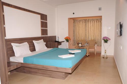 ein Schlafzimmer mit einem großen Bett und einem Tisch in der Unterkunft Hotel Emerald Dove in Yelagiri