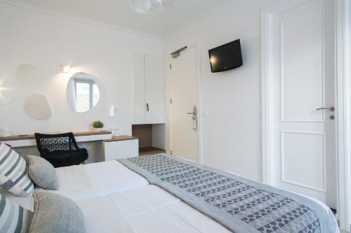 a white bedroom with a bed and a tv on the wall at Aurora - Rooms & Suites - Spetses in Spetses