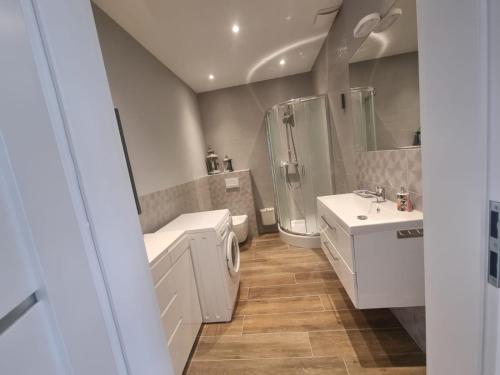 a white bathroom with a shower and a sink at Apartament Milena in Kruszyn