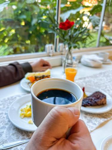a person holding a cup of coffee on a table at Pousada Cabanas Rota do Sol in Gramado