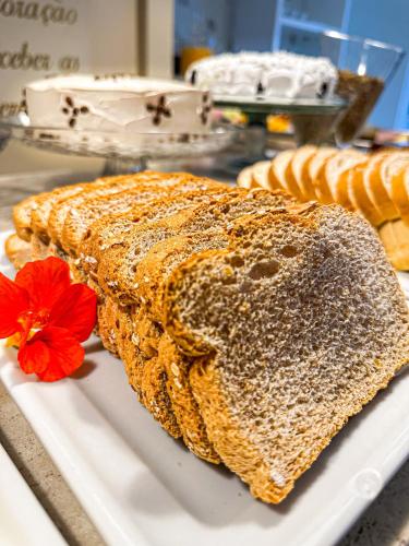 two slices of bread on a white plate with a red flower at Pousada Cabanas Rota do Sol in Gramado
