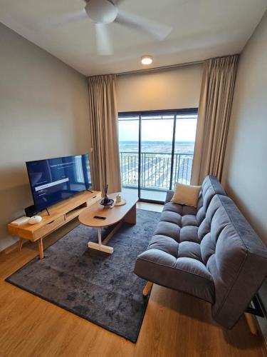 a living room with a large couch and a television at Mayabay Gamuda Cove SplashMania Suite in Banting