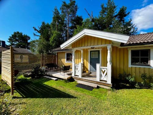 a small yellow house with a wooden porch at Jacobs Stuga in Furudal