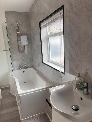 a bathroom with a tub and a sink and a mirror at Cozy Haven near Glenfield & LRI Hospitals in Leicester
