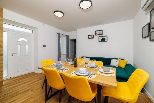 a dining room with a table and yellow chairs at House Scaena in Jadranovo