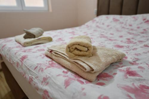 two towels are sitting on a bed with flowers at Apartman Poezija in Bajina Bašta