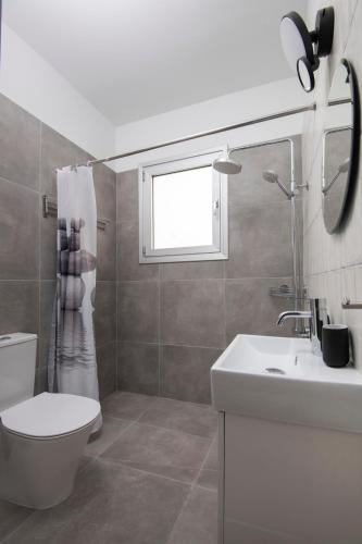 a bathroom with a toilet and a sink and a window at Amazing Two Bedroom Apartment in Larnaca