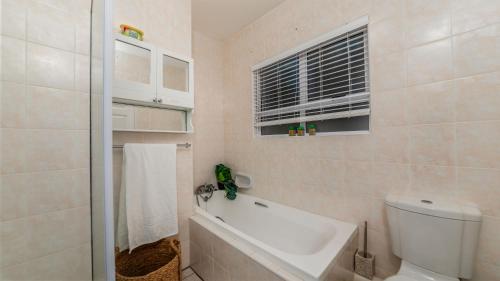 a bathroom with a tub and a toilet and a window at 10 Malibu, Beverly Hills Estate in Ballito