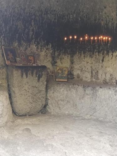 a wall with a shelf with pictures and candles at Vardzia Old Village in Vardzia