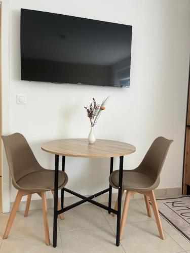 a table with two chairs and a vase with flowers at AppartHôtel Elite Spa in Forbach