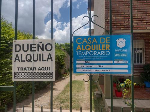 two signs on a fence in front of a building at Depto mina clavero Córdoba zona residencial in Mina Clavero