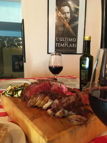 a piece of meat on a cutting board with a glass of wine at Agriturismo Corte Marani in Badia Calavena