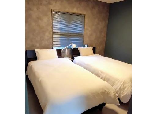 a bedroom with two beds with white sheets and a window at FAB IN - Vacation STAY 41993v in Naha