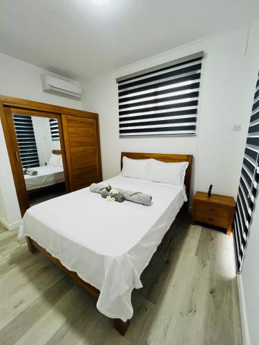 a bedroom with a large white bed and two windows at Seascape Modern Accomodation Near CLUB MED ALBION in Albion