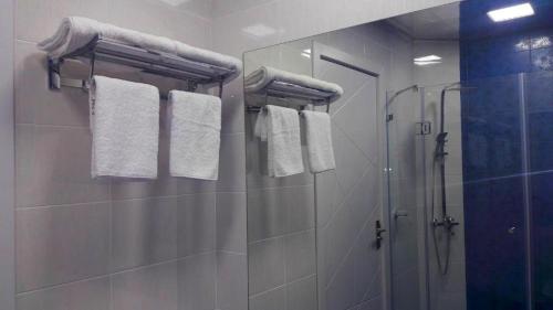 a bathroom with a shower and white towels at Hotel Lilo near Airport in Tbilisi City
