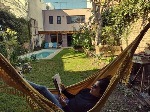 Eine Frau, die in einer Hängematte liegt und ein Buch liest. in der Unterkunft Casa San Isidro pileta jardín parrilla a metros del río in San Isidro