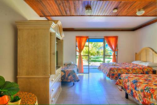 a bedroom with two beds and a tv and a window at Beach Break Resort & CR Surf Camp in Jacó