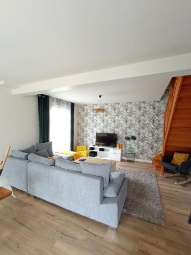 un salon avec un canapé bleu et une télévision dans l'établissement Maison de charme, à Plancoët