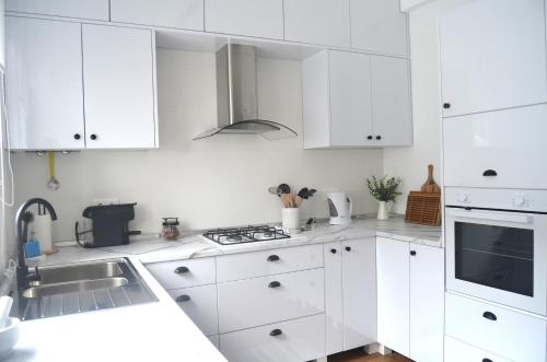 a white kitchen with white cabinets and a sink at Quinta Peixinho RC DT in Horta