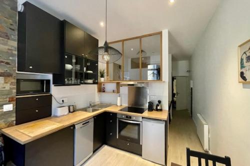 une cuisine avec des armoires en noir et blanc et un comptoir dans l'établissement Le Rousseau - Beautiful studio in Old Town, à Annecy