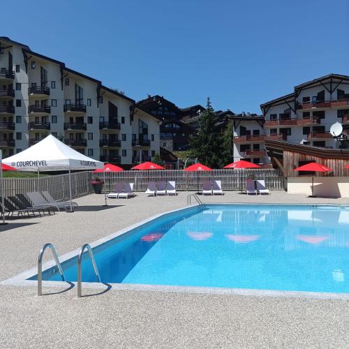 une piscine avec chaises et parasols à côté d'un bâtiment dans l'établissement Ski-in ski-out 1 bed, La Tania, à Courchevel