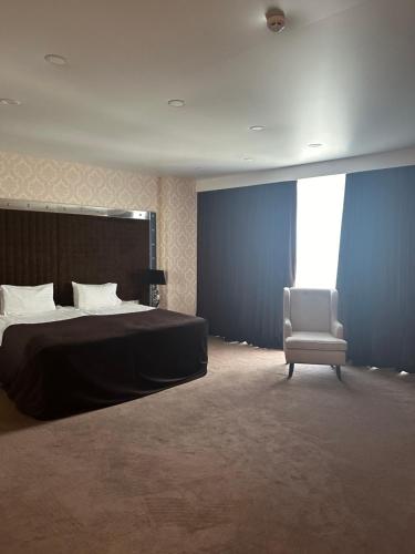 a bedroom with a bed and a white chair at Maristella Marine Residense Hotel Apartment in Odesa