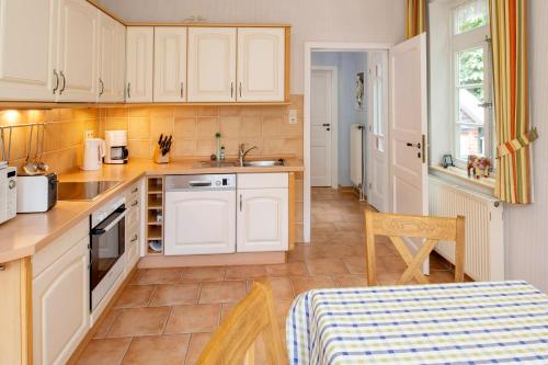 Una cocina con gabinetes blancos y una mesa en ella. en Insulanerhaus Langeoog Vörn, en Langeoog