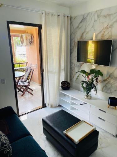 a living room with a couch and a tv at Piscina, Mar e estilo em Angra dos Reis in Angra dos Reis