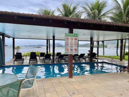 a swimming pool with chairs and a sign next to it at Piscina, Mar e estilo em Angra dos Reis in Angra dos Reis