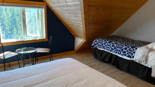 a bedroom with two beds and a table and a window at Canmore Alpine Hostel - Alpine Club of Canada in Canmore