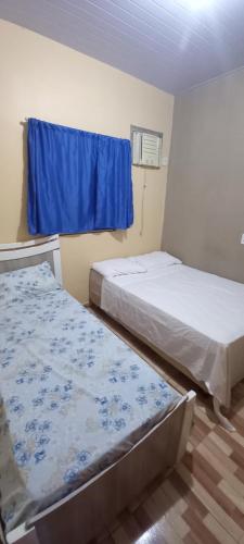 two beds in a small room with a blue window at Casa de temporada SONHO DE ALTER in Alter do Chao