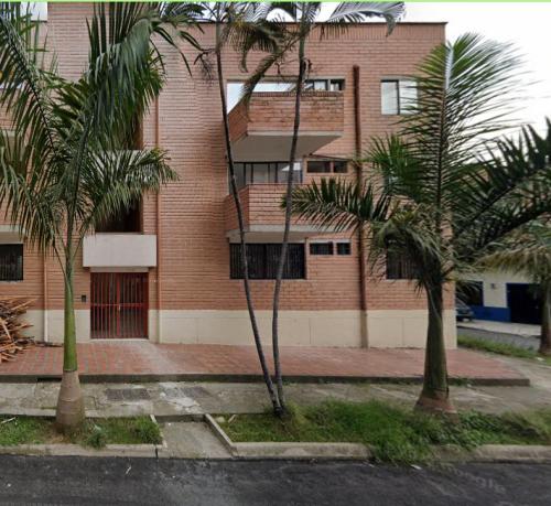 a brick building with palm trees in front of it at Céntrico Familiar Vive y disfruta Medellín 107 in Medellín