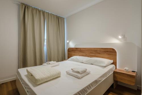 a white bedroom with a bed with towels on it at Casanova Bluelife in Trieste