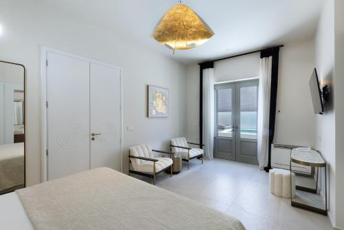 a bedroom with a bed and chairs and a window at La Madeleine Oia in Oia