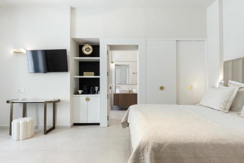 a white bedroom with a bed and a table at La Madeleine Oia in Oia