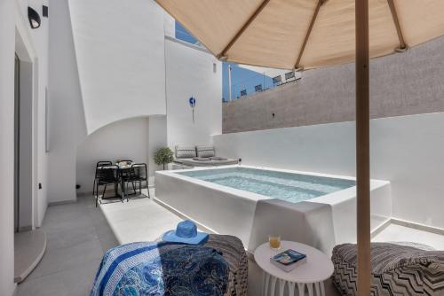 a swimming pool in a building with an umbrella at La Madeleine Oia in Oia