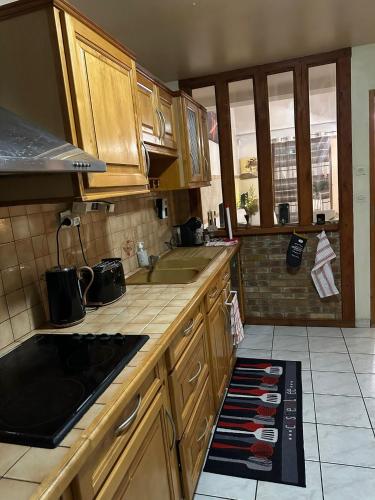 une cuisine avec des armoires en bois et un comptoir dans l'établissement Belle maison confortable, à Montfermeil