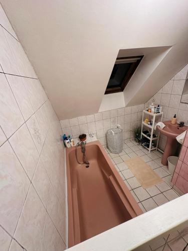 a bathroom with a pink tub and a sink at Belle maison confortable in Montfermeil