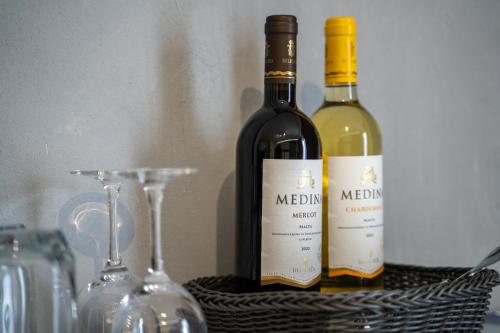 two bottles of wine in a basket next to glasses at The Republic Boutique Hotel in Valletta