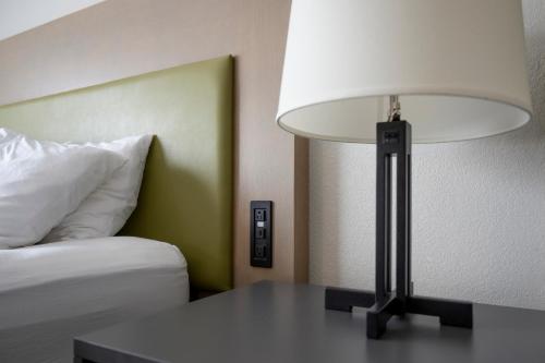 a lamp sitting on a table next to a bed at Country Inn & Suites by Radisson, Queensbury - Lake George , NY in Lake George
