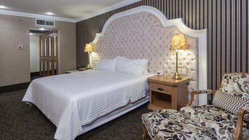 a bedroom with a large white bed and a chair at Holiday Inn Queretaro Centro Historico by IHG in Querétaro