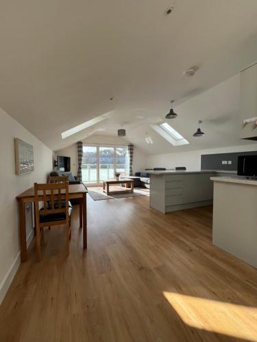 a living room with a table and a kitchen at The Boathouse in Mylor Bridge