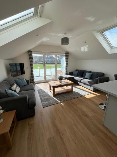 a living room with couches and a table at The Boathouse in Mylor Bridge