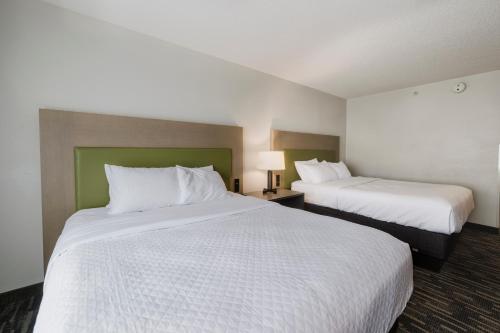 a hotel room with two beds with white sheets at Country Inn & Suites by Radisson, Queensbury - Lake George , NY in Lake George