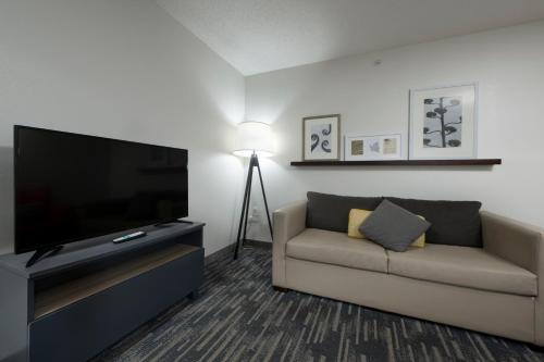 a living room with a couch and a flat screen tv at Country Inn & Suites by Radisson, Queensbury - Lake George , NY in Lake George