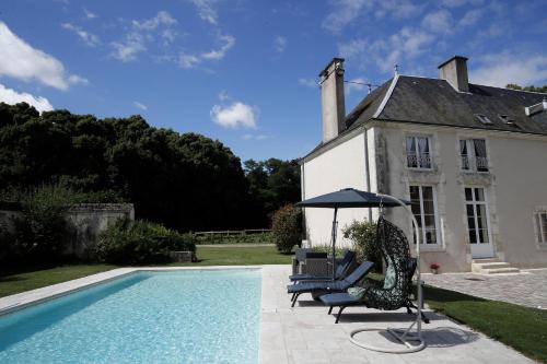 a pool with chairs and an umbrella next to a house at Chambres d'hôtes chez Sylvie in Donnemain-Saint-Mamès